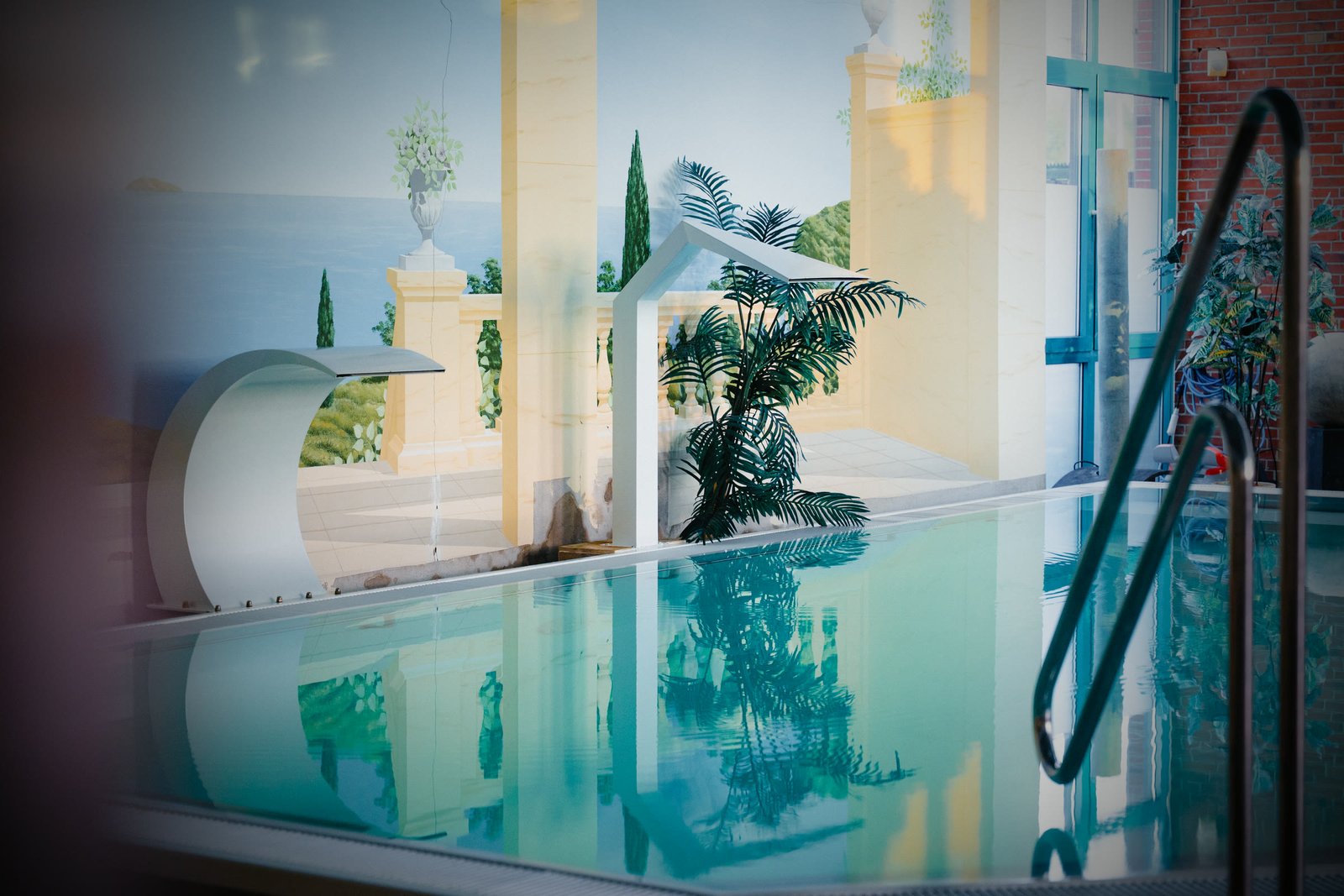 Das ruhige, leere Becken mit Wasserfall und Palme, die sich im Wasser spiegeln